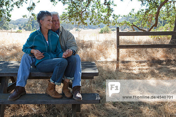 Mature couple sitting on picnic table
