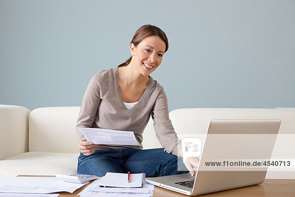 Young woman with paperwork using laptop