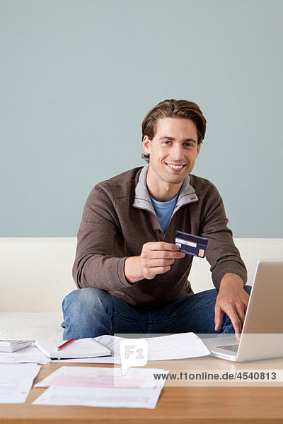 Junger Mann mit Kreditkarte mit laptop