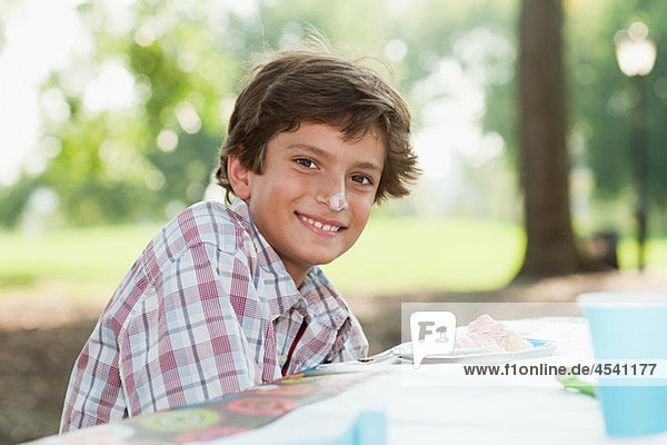 Boy at birthday party with birthday cake on his nose
