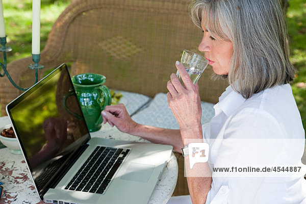 Reife Frau mit Laptop-Trinkwasser
