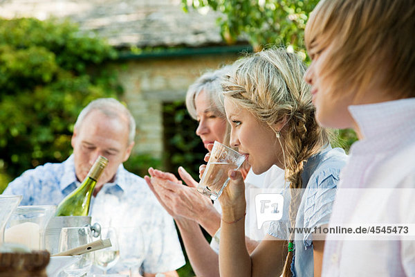 Junge Frau trinkt Wasser mit Familie