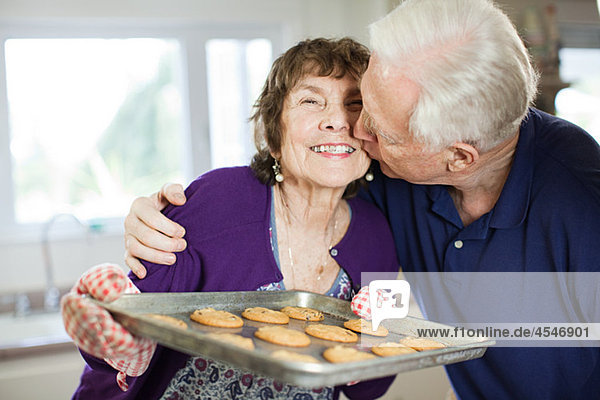 Seniorenpaar beim Küssen mit selbstgebackenen Keksen