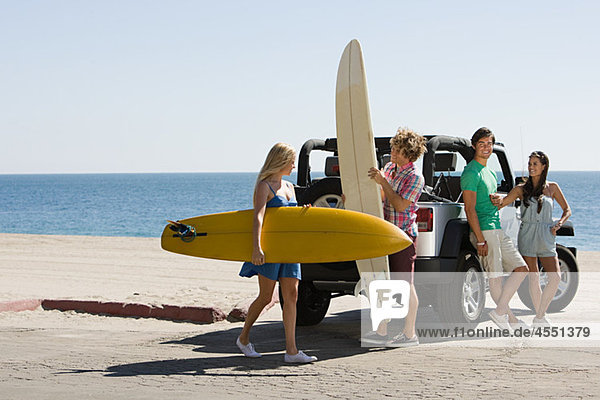 Friends by vehicle with surfboards