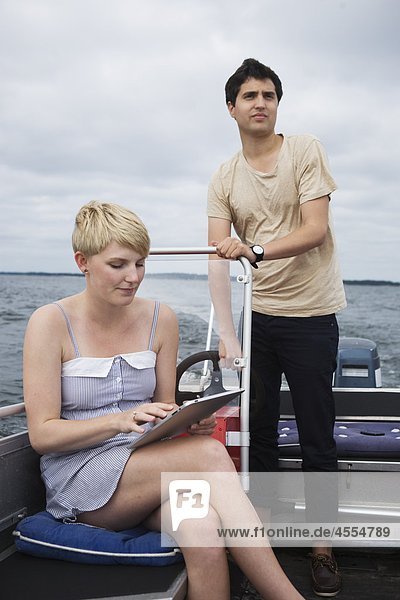 Young couple on boat using GPS device