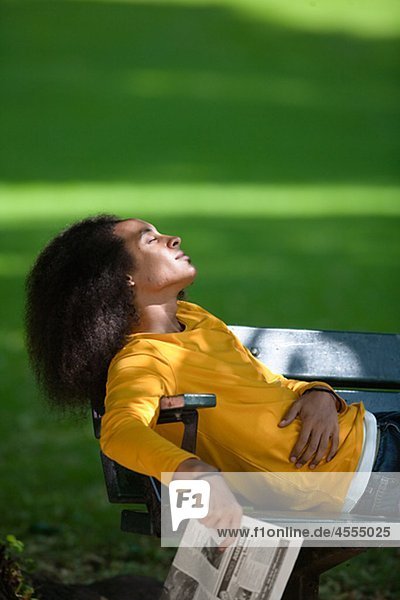 Young man with afro hair relaxing on bench