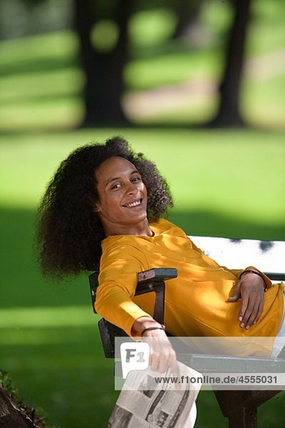 Smiling young man with afro hair relaxing on bench