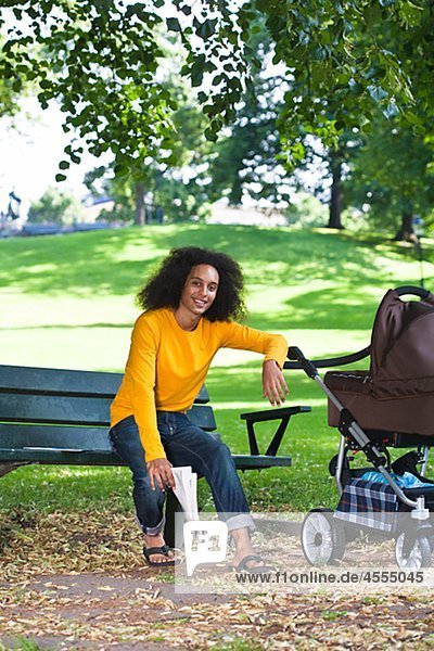 Smiling young man with baby carriage sitting on bench