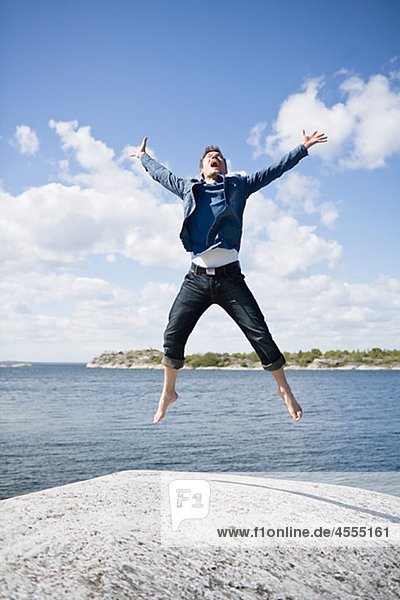 Mid adult man jumping on coastline