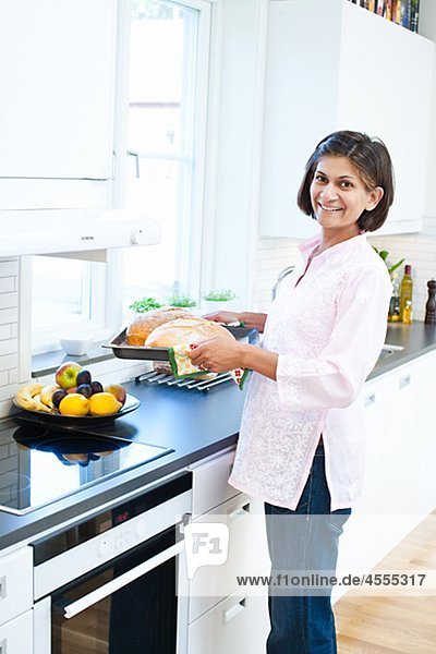 Portrait of Frau hält Brot auf Tablett in Küche