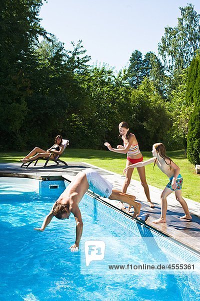 Children pushing father into swimming pool