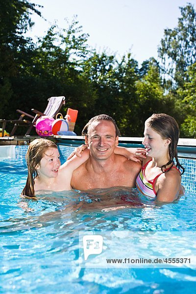 Portrait of father with two children in swimming pool