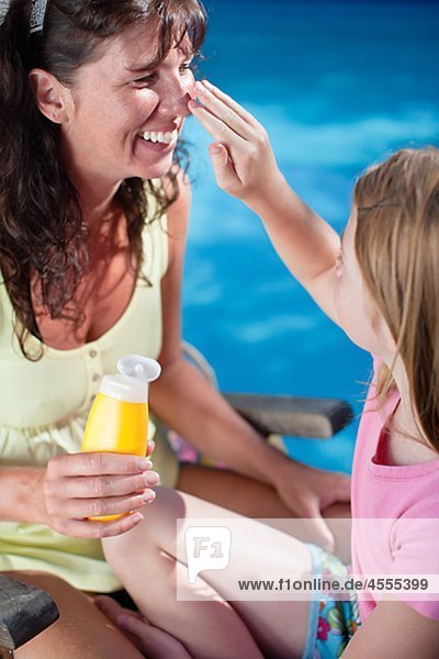 Girl applying suntan lotion on her mothers nose