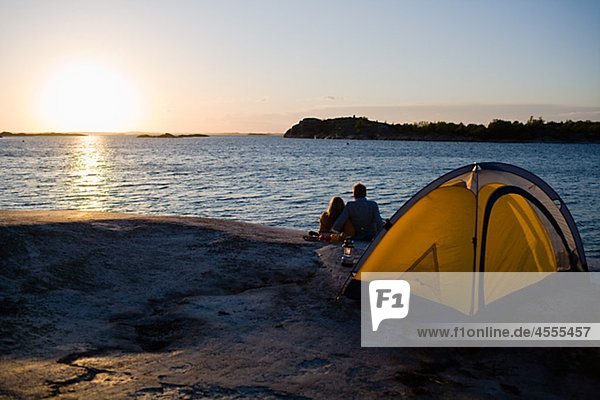 Couple camping by sea at sunset