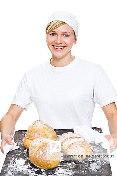 Frau hält Backblech mit Brot Lächeln portrait