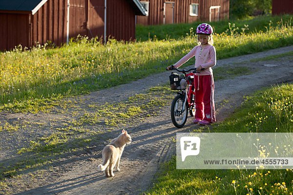 Mädchen mit Fahrrad in der Nähe von Cat im Dorf
