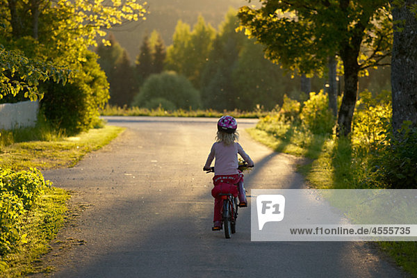 Girl riding bicycle on country road