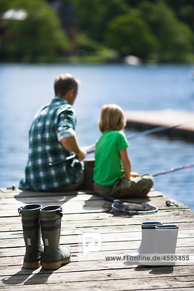 Father with son fishing rubber boots on foreground