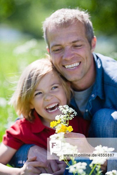 Vater und Sohn mit Blumen  in hellem Sonnenlicht