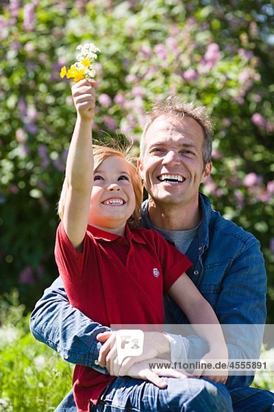 Vater und Sohn mit Blumen in hellem Sonnenlicht