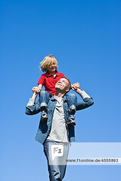 Vater Piggy Backing Tochter gegen Wolkenloser Himmel
