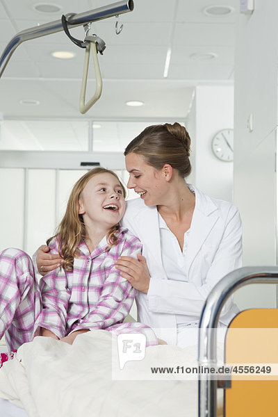 Krankenschwester und Mädchen im Krankenhausbett  lachend