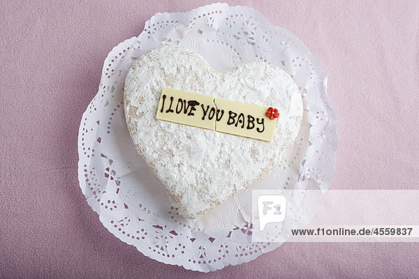 Herzförmiges Gebäck mit Schriftzug auf dekorativer weißer Schokolade  ''I love you baby'''.