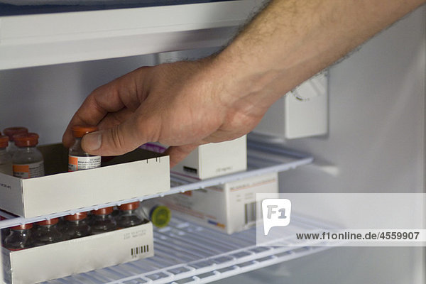 Medizinischer Fachmann beim Entfernen von Medikamentenfläschchen aus dem Kühlschrank