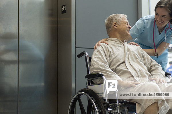 Krankenschwester hilft Patientin im Rollstuhl