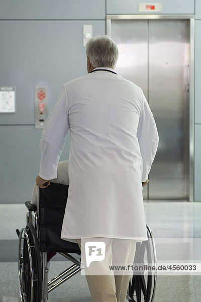 Arzt schiebt Patient im Rollstuhl