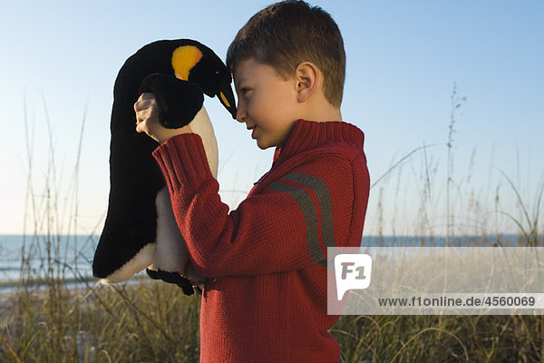 Boy nuzzling stuffed toy penguin