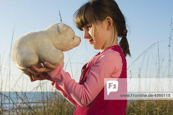 Young girl face to face with stuffed toy polar bear cub