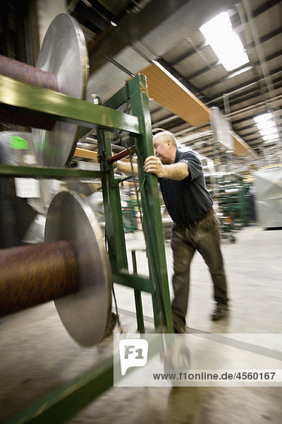 Textilarbeiter beim Einrichten von Kettbäumen auf der Webmaschine in der Teppichfliesenfabrik