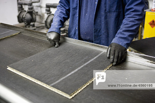 Fabrikarbeiter prüft Qualität der Teppichfliesen