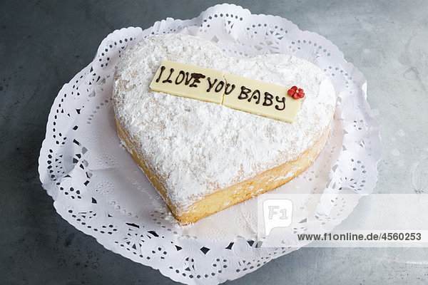 Herzförmiges Gebäck mit Schriftzug auf dekorativer weißer Schokolade  ''I love you baby'''.