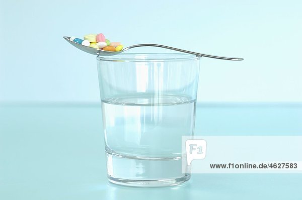 Pillen im Löffel auf Wasserglas