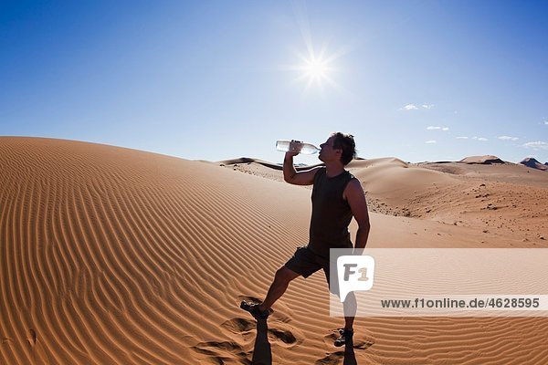 Afrika  Namibia  Namib Wüste  Namib Naukluft Nationalpark  reifer Mann Trinkwasser aus der Wasserflasche
