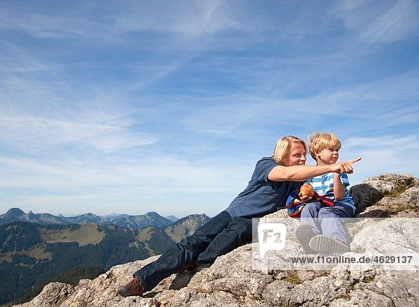 Deutschland  Bayern  Vater und Sohn (4-5 Jahre) sitzend auf dem Berggipfel