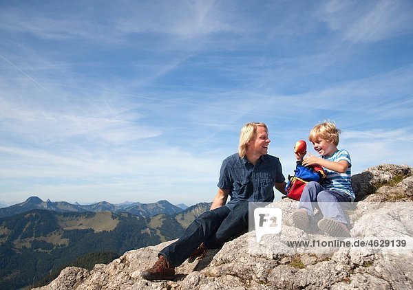 Deutschland  Bayern  Vater und Sohn (4-5 Jahre) blicken mit Karte auf den Berggipfel