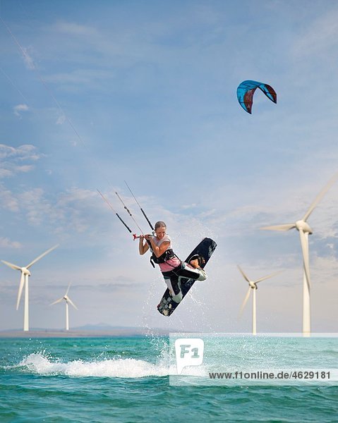 Kroatien Zadar Kitesurfer springen vor der Windkraftanlage
