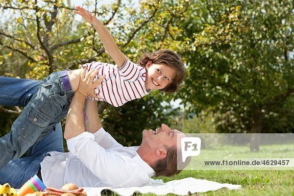 Deutschland  Bayern  Vater und Tochter (8-9 Jahre) beim Picknick  lachend