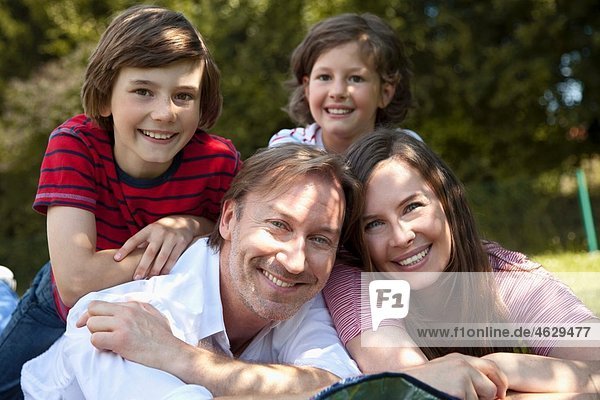 Deutschland  Bayern  Familie auf Gras liegend  lächelnd  Portrait