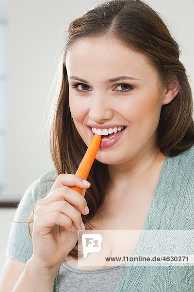 Junge Frau isst Karotte  Porträt