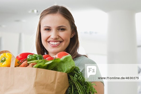 Junge Frau mit Tasche voller Gemüse  lächelnd  Portrait