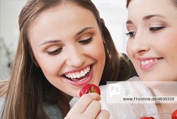 Junge Frauen essen Erdbeere  lächelnd