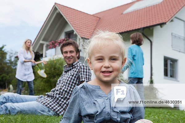 Mädchen (2-3 Jahre) lächelnd mit Familie im Hintergrund