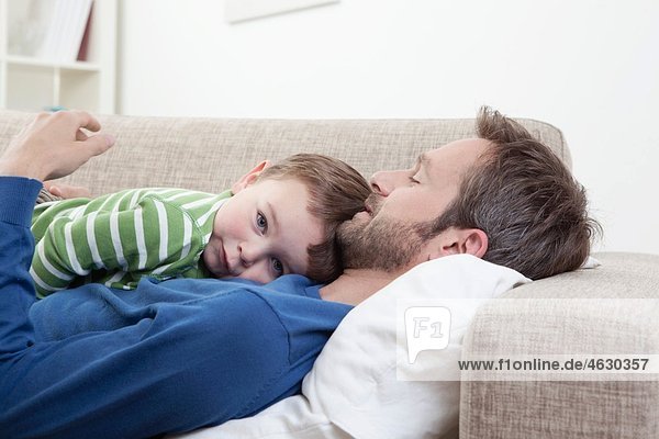 Germany  Bavaria  Munich  Father and son (2-3 Years) resting on sofa