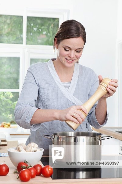 Frau bereitet Essen in der Küche zu  lächelnd