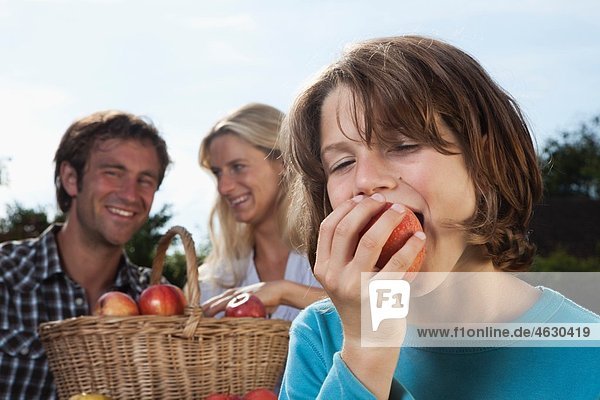 Deutschland  München  Familie isst Äpfel im Garten