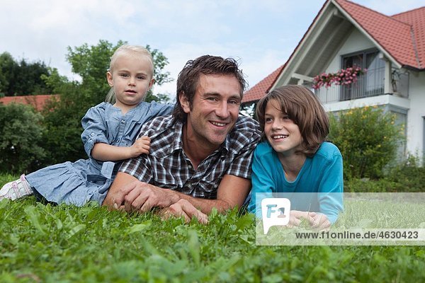 Deutschland  München  Vater mit Kindern im Garten  lächelnd